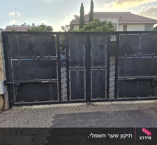 שער חשמלי כפול ממתכת שחורה עם מנועי זרוע בכניסה לבית